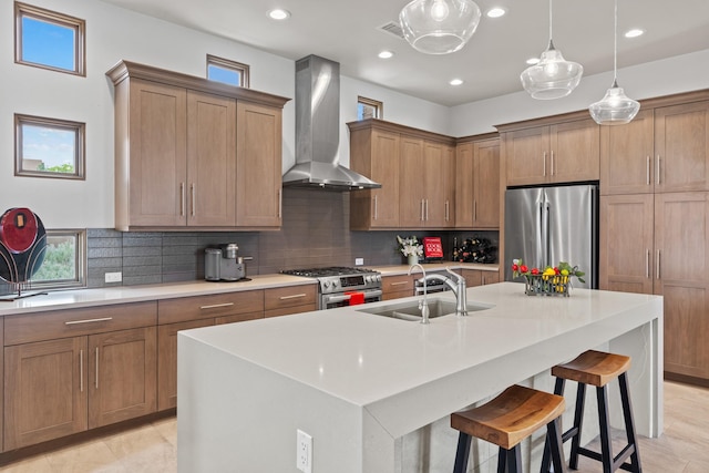 kitchen with a breakfast bar area, plenty of natural light, a sink, appliances with stainless steel finishes, and wall chimney exhaust hood