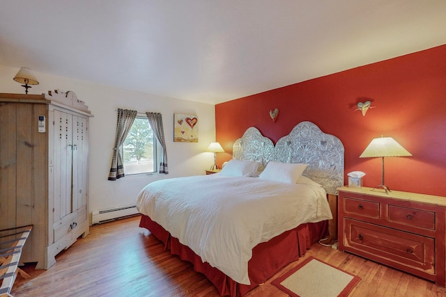 bedroom featuring a baseboard heating unit and light wood-type flooring