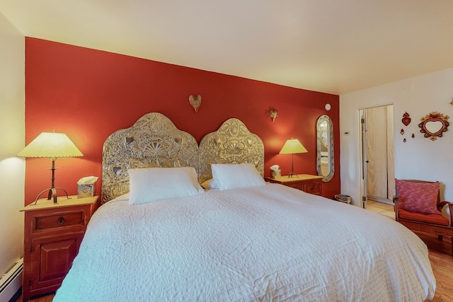 bedroom featuring a baseboard heating unit and light hardwood / wood-style floors