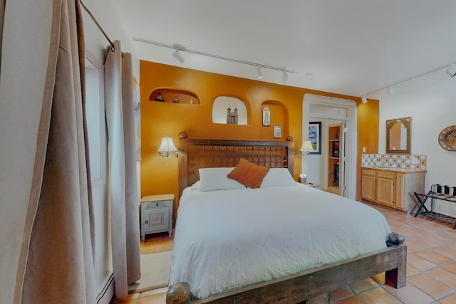 bedroom featuring a baseboard radiator, track lighting, and light tile floors