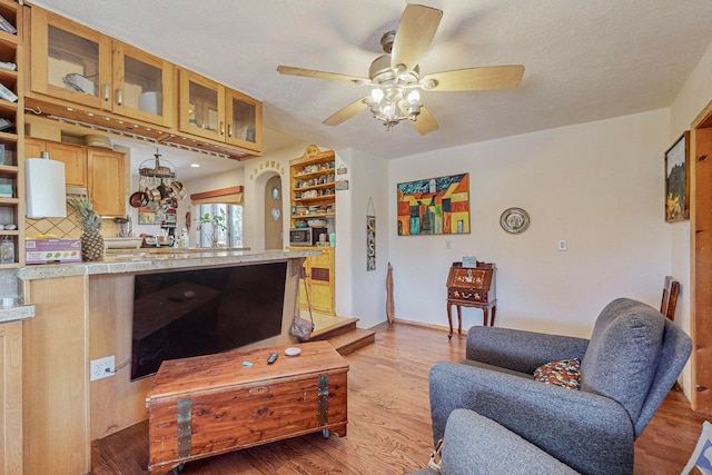 living room with ceiling fan, a textured ceiling, and light wood-type flooring