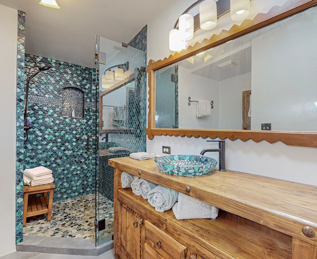 bathroom with tile flooring, vanity with extensive cabinet space, and a shower with shower door