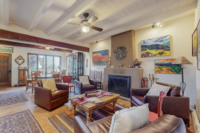 living room with a baseboard radiator, a fireplace, light wood-type flooring, beamed ceiling, and ceiling fan