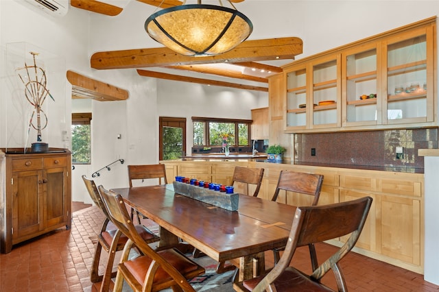 dining area featuring a towering ceiling, sink, and a wall unit AC