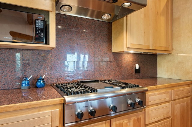 kitchen with stainless steel gas stovetop, light brown cabinets, wall chimney exhaust hood, and tasteful backsplash