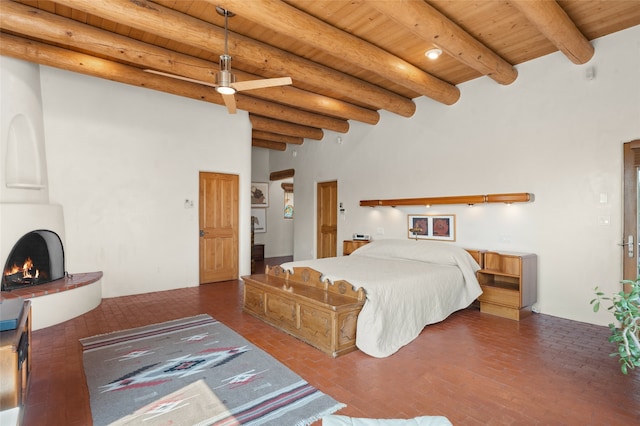 bedroom featuring wooden ceiling, a high ceiling, a large fireplace, and beamed ceiling