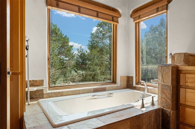 bathroom featuring a relaxing tiled tub and plenty of natural light