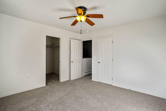 unfurnished bedroom featuring a ceiling fan, carpet flooring, baseboards, baseboard heating, and a spacious closet