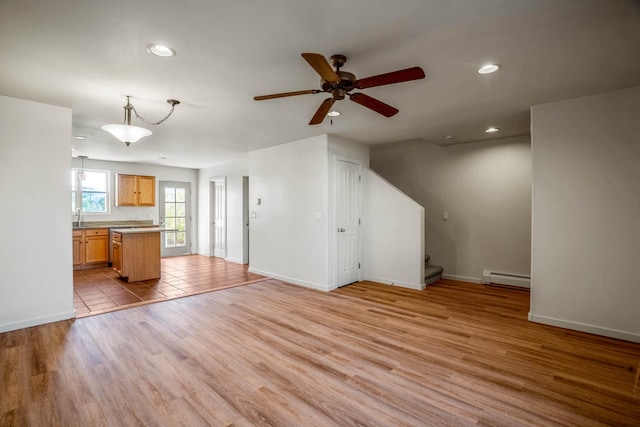 unfurnished living room featuring recessed lighting, light wood-type flooring, stairs, and a baseboard radiator