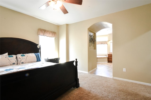 carpeted bedroom with ceiling fan, multiple windows, and ensuite bath