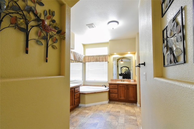 bathroom with a bath to relax in, vanity, and tile floors