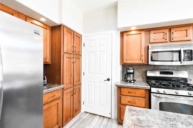 kitchen featuring backsplash, appliances with stainless steel finishes, and light wood-type flooring