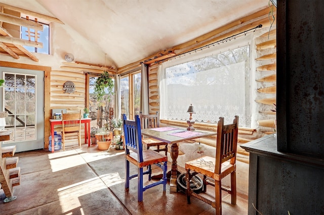 dining area with vaulted ceiling, rustic walls, and a healthy amount of sunlight