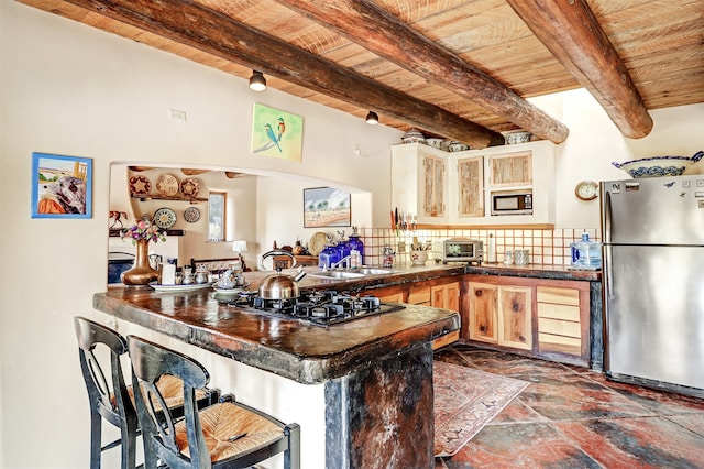 kitchen featuring beam ceiling, appliances with stainless steel finishes, and kitchen peninsula