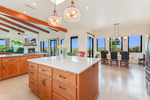 kitchen with light stone counters, ceiling fan, pendant lighting, lofted ceiling with beams, and a center island