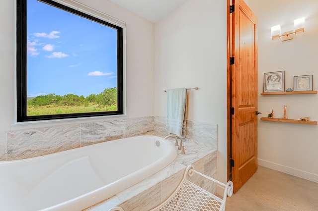 bathroom featuring a relaxing tiled tub and a healthy amount of sunlight