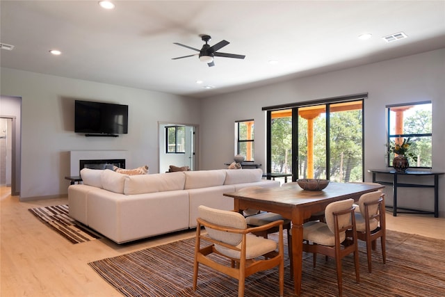 dining area with a ceiling fan, visible vents, light wood-style flooring, recessed lighting, and a glass covered fireplace