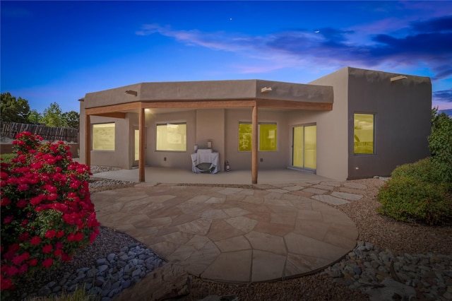 back house at dusk featuring a patio