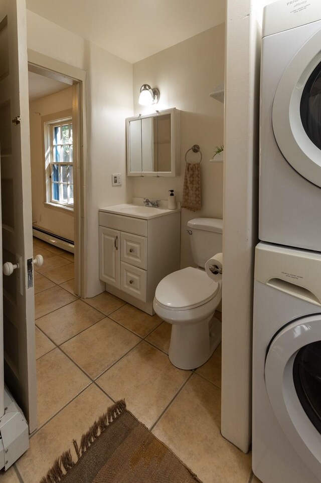 bathroom featuring vanity, a baseboard heating unit, tile patterned floors, toilet, and stacked washing maching and dryer