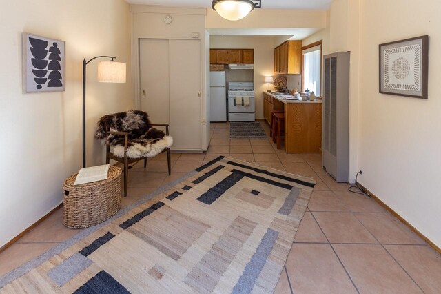 kitchen featuring sink, light tile patterned flooring, and white appliances