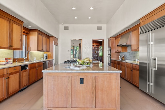 kitchen with a kitchen island, light tile patterned flooring, appliances with stainless steel finishes, and wall chimney exhaust hood