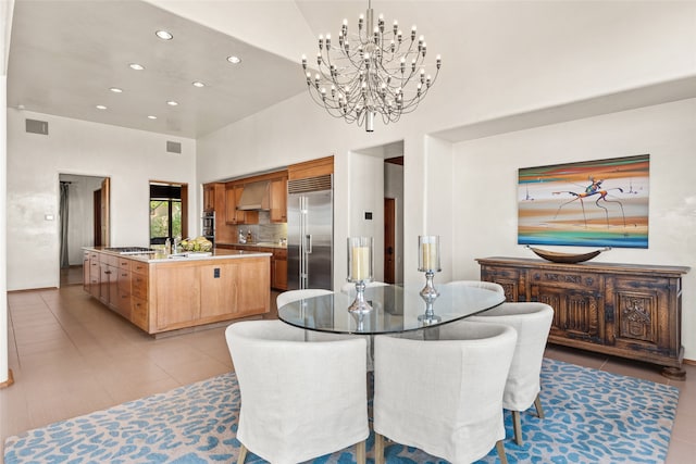 dining room with a high ceiling, light tile patterned flooring, sink, and a notable chandelier