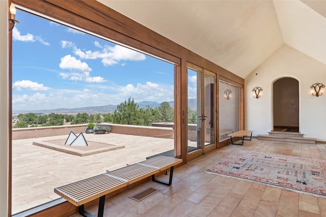 unfurnished sunroom with a mountain view, a healthy amount of sunlight, and lofted ceiling