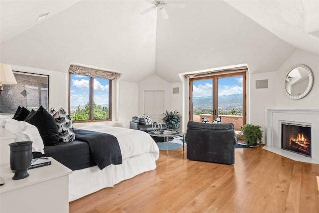 bedroom with hardwood / wood-style flooring, lofted ceiling, access to exterior, and multiple windows