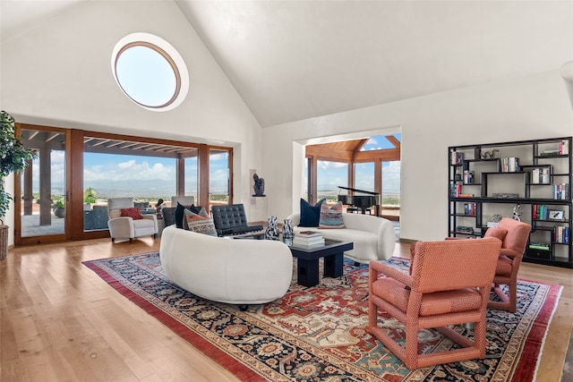 living room with hardwood / wood-style flooring, a healthy amount of sunlight, and high vaulted ceiling