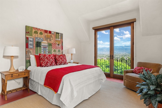 bedroom featuring hardwood / wood-style flooring, lofted ceiling, a mountain view, and access to exterior