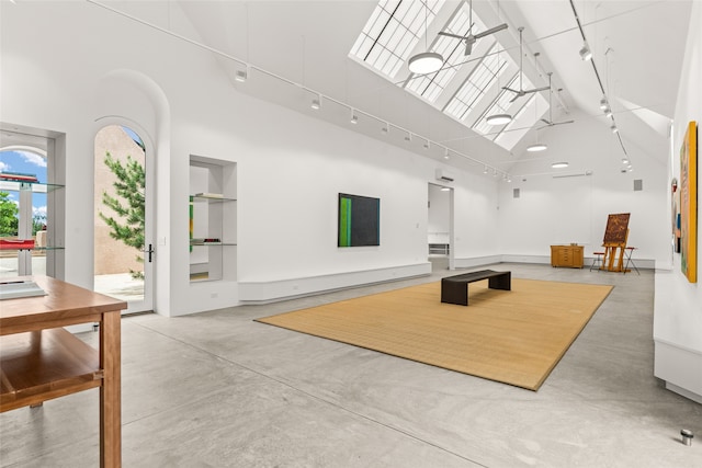 exercise room with a towering ceiling, track lighting, and built in shelves