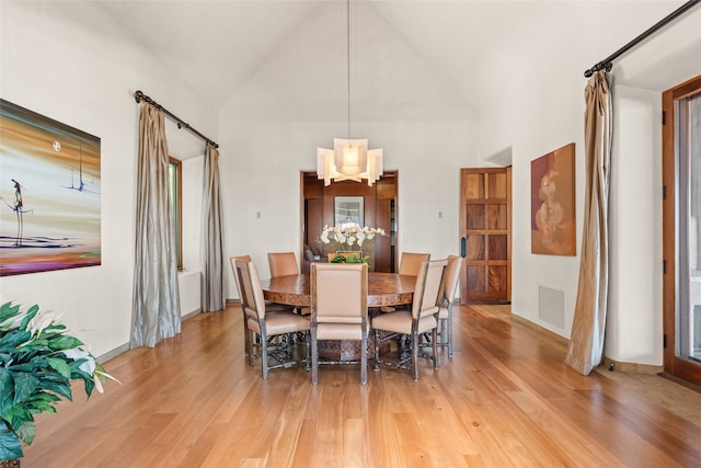 dining area with high vaulted ceiling and light wood-type flooring