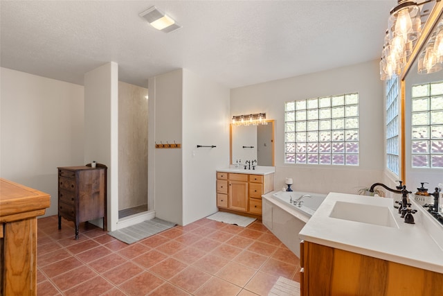 bathroom featuring vanity, a textured ceiling, tiled bath, and tile patterned floors