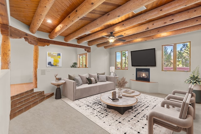 living room featuring beamed ceiling, ceiling fan, wooden ceiling, and carpet