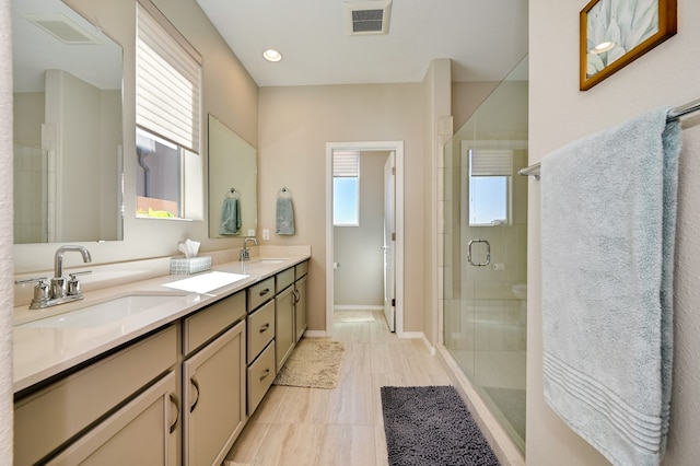 bathroom featuring a healthy amount of sunlight, a shower with shower door, and vanity