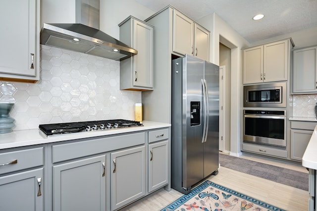 kitchen featuring gray cabinets, appliances with stainless steel finishes, and wall chimney exhaust hood