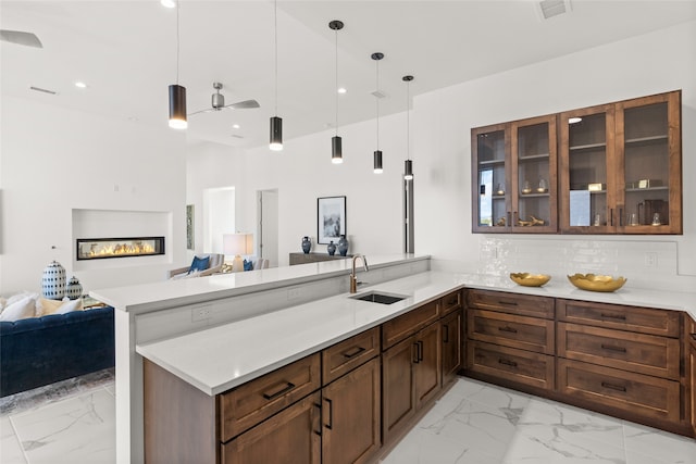 kitchen with marble finish floor, a sink, open floor plan, a peninsula, and light countertops