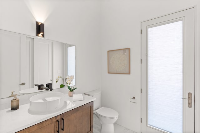 bathroom with toilet, marble finish floor, and vanity