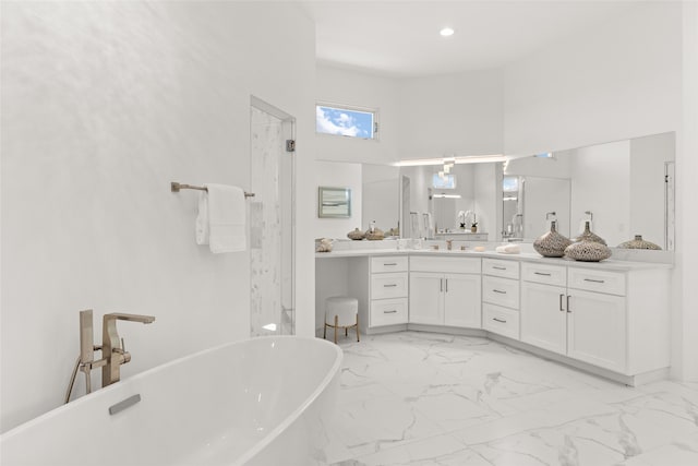 full bathroom featuring recessed lighting, marble finish floor, vanity, and a freestanding tub