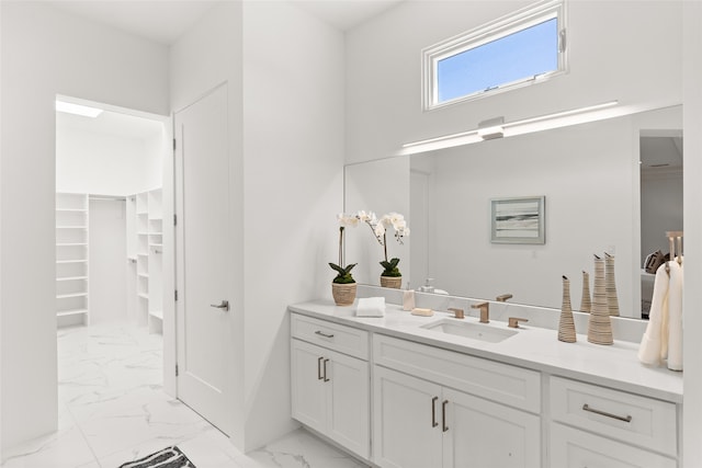 bathroom featuring a spacious closet, a high ceiling, marble finish floor, and vanity