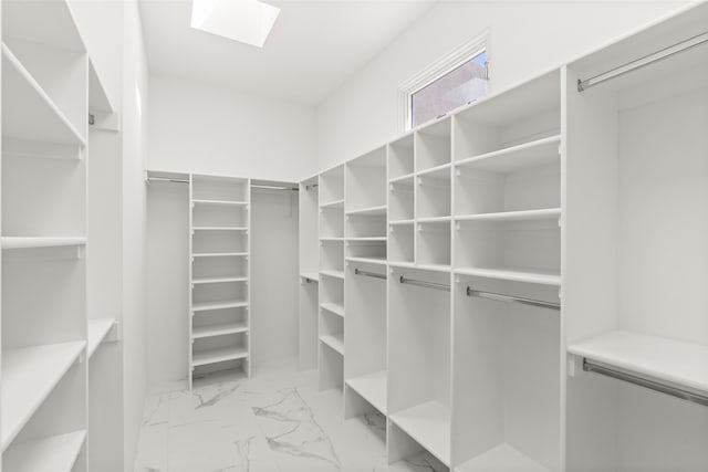 spacious closet featuring a skylight and marble finish floor