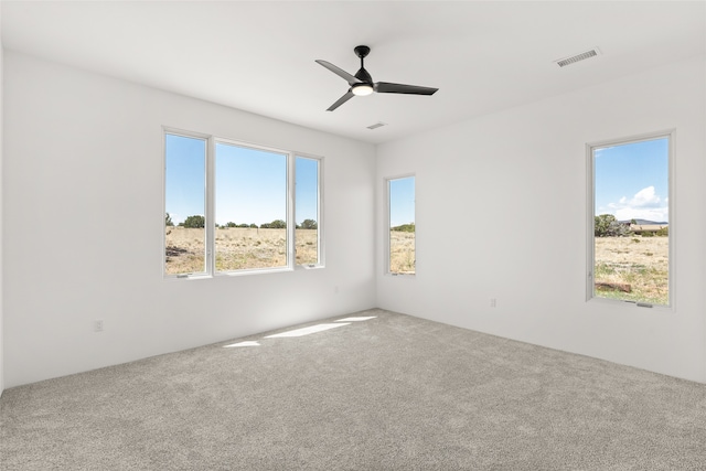 empty room with visible vents, plenty of natural light, a ceiling fan, and carpet floors