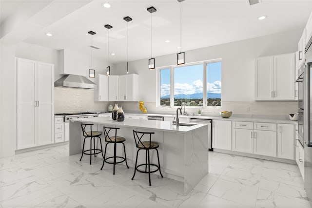 kitchen featuring light tile patterned flooring, wall chimney range hood, an island with sink, and backsplash