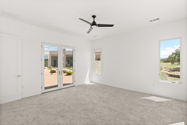 carpeted empty room with visible vents, a ceiling fan, and french doors