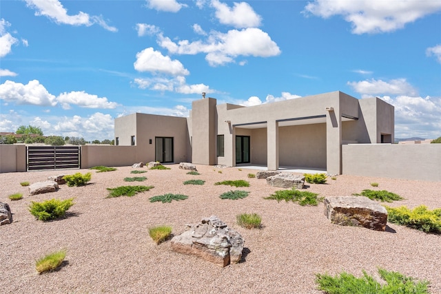 rear view of property featuring stucco siding and fence