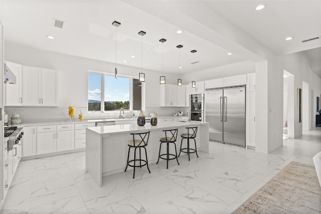 kitchen featuring a kitchen bar, marble finish floor, tasteful backsplash, a center island, and stainless steel appliances