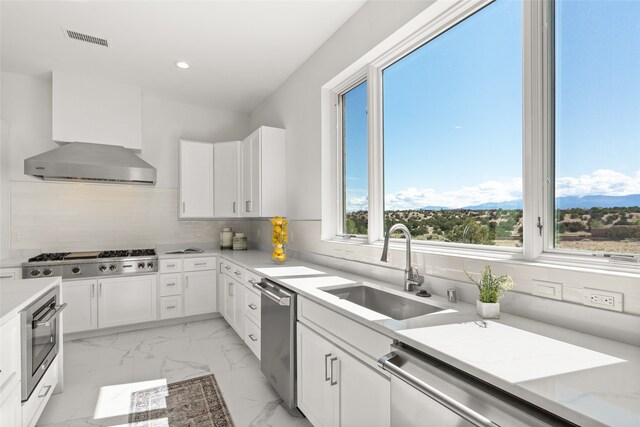 kitchen with visible vents, a sink, stainless steel appliances, wall chimney exhaust hood, and marble finish floor