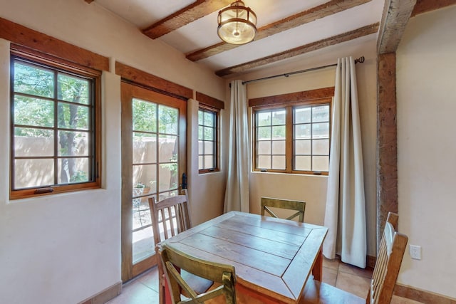 dining room featuring beamed ceiling and light tile patterned flooring