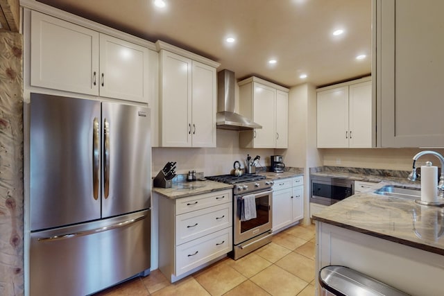 kitchen featuring white cabinetry, sink, wall chimney exhaust hood, light stone counters, and appliances with stainless steel finishes