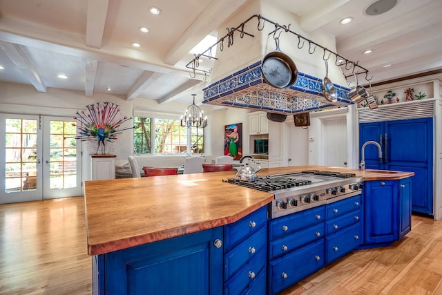 kitchen with blue cabinets, an island with sink, stainless steel gas cooktop, and light wood-type flooring